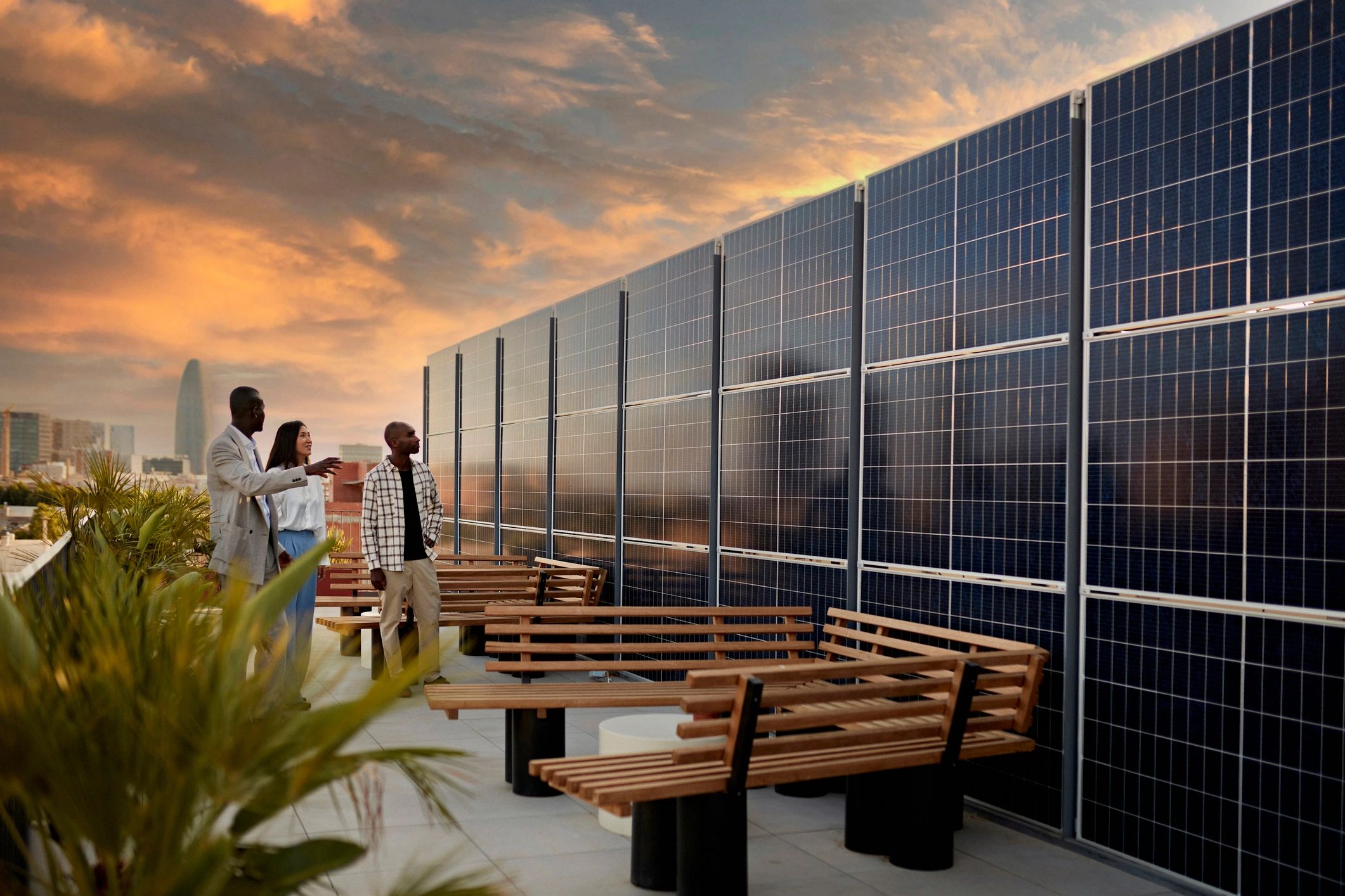 People on a rooftop near solar panels at sunset